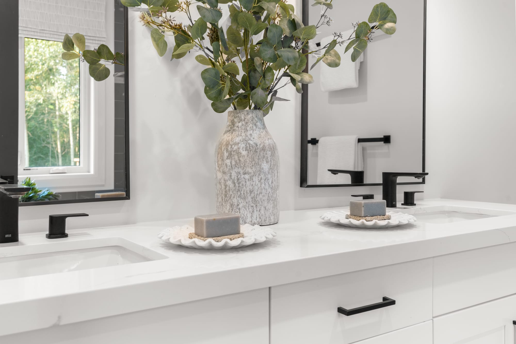 Close-up of the ensuite quartz vanity with eucalyptus stems and matte black taps at 110 Mary Street, Collingwood