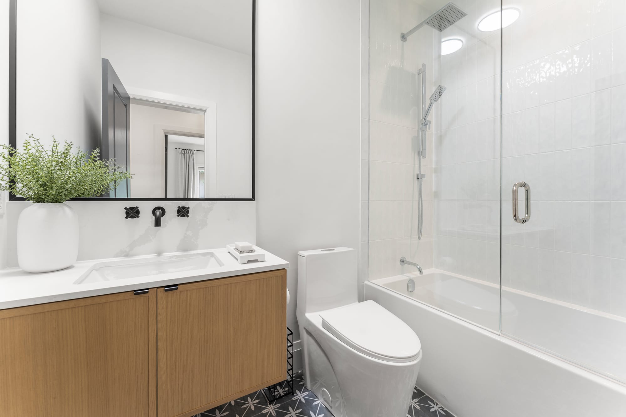 Main bathroom with a white oak floating vanity, tub and shower combination and patterned floor tile