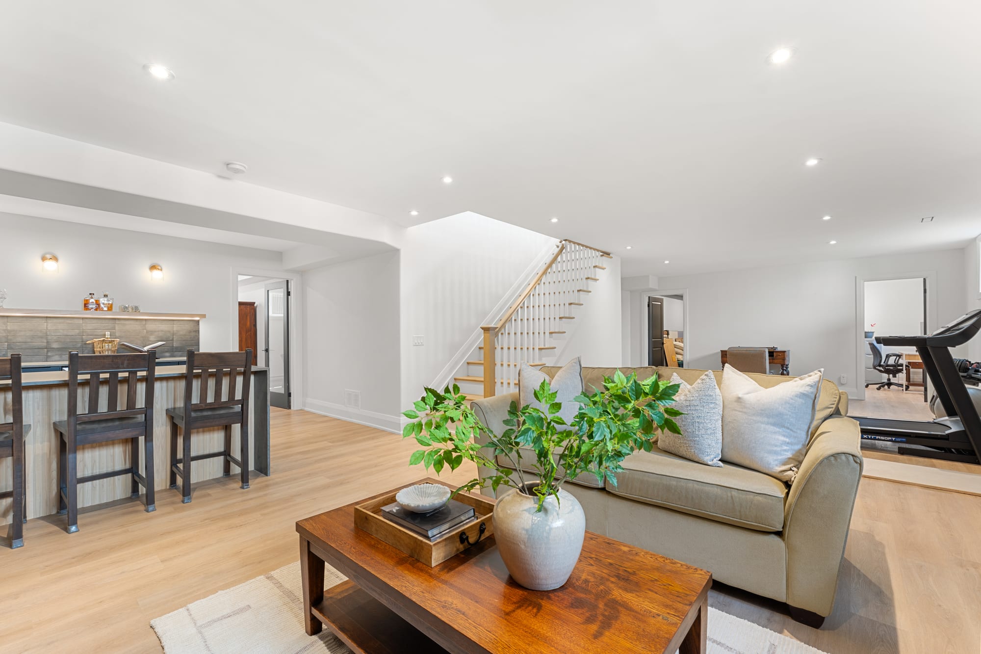 Recreation room looking toward the staircase, with the home office and gym area visible through open doorways