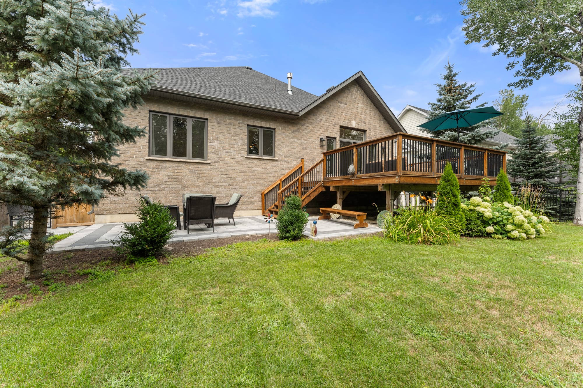 Rear exterior of 110 Mary Street, Collingwood, with the raised cedar deck, lower stone patio and hydrangea beds