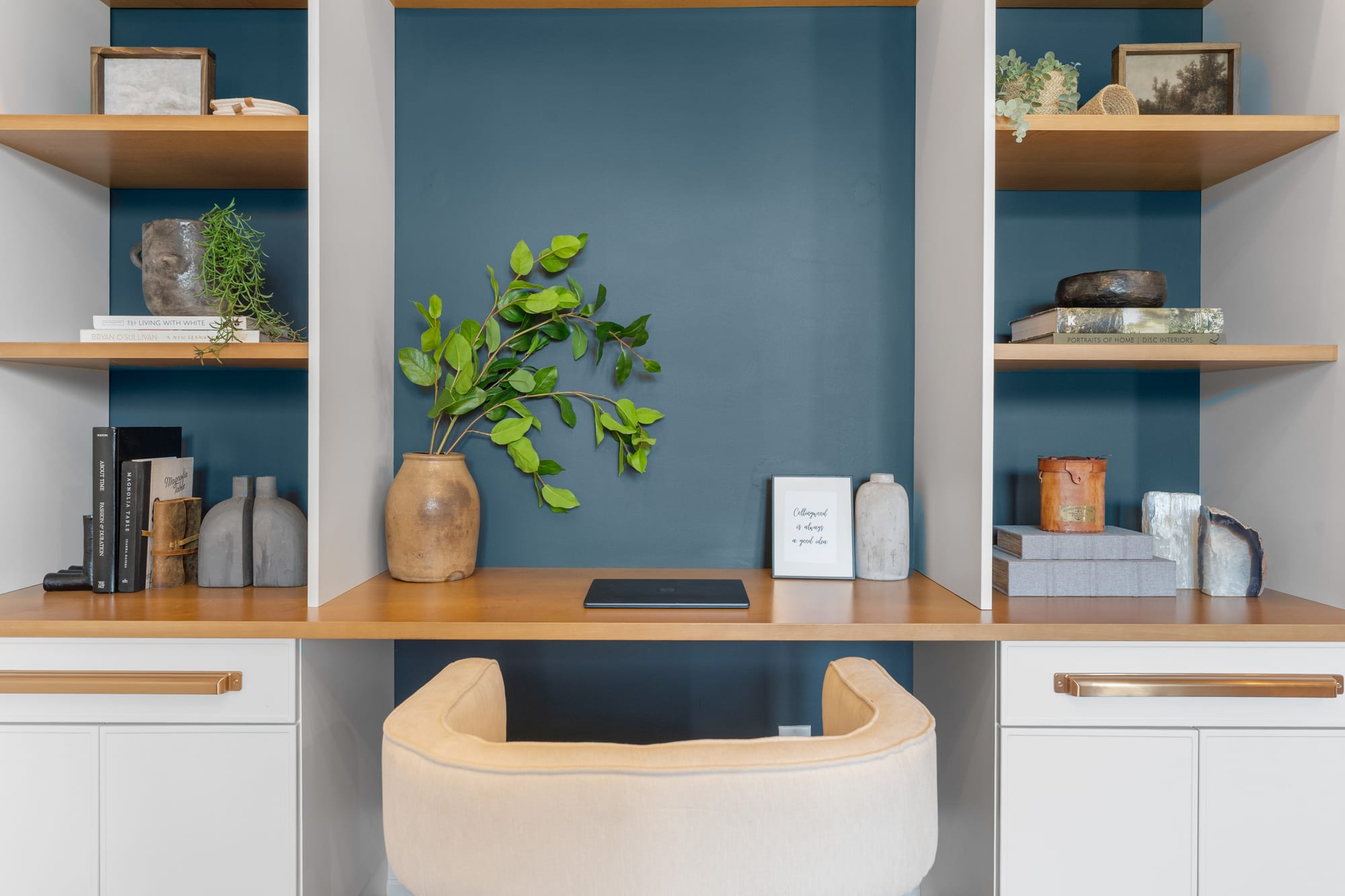 Built-in home office nook with oak shelving, a deep blue painted back panel and a "Collingwood is always a good idea" print